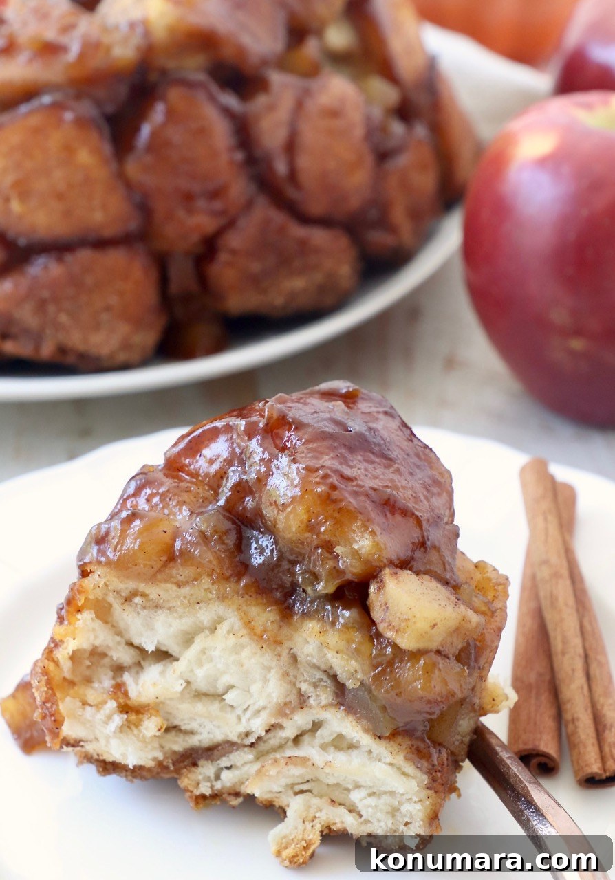 slice of apple monkey bread on plate with cinnamon sticks