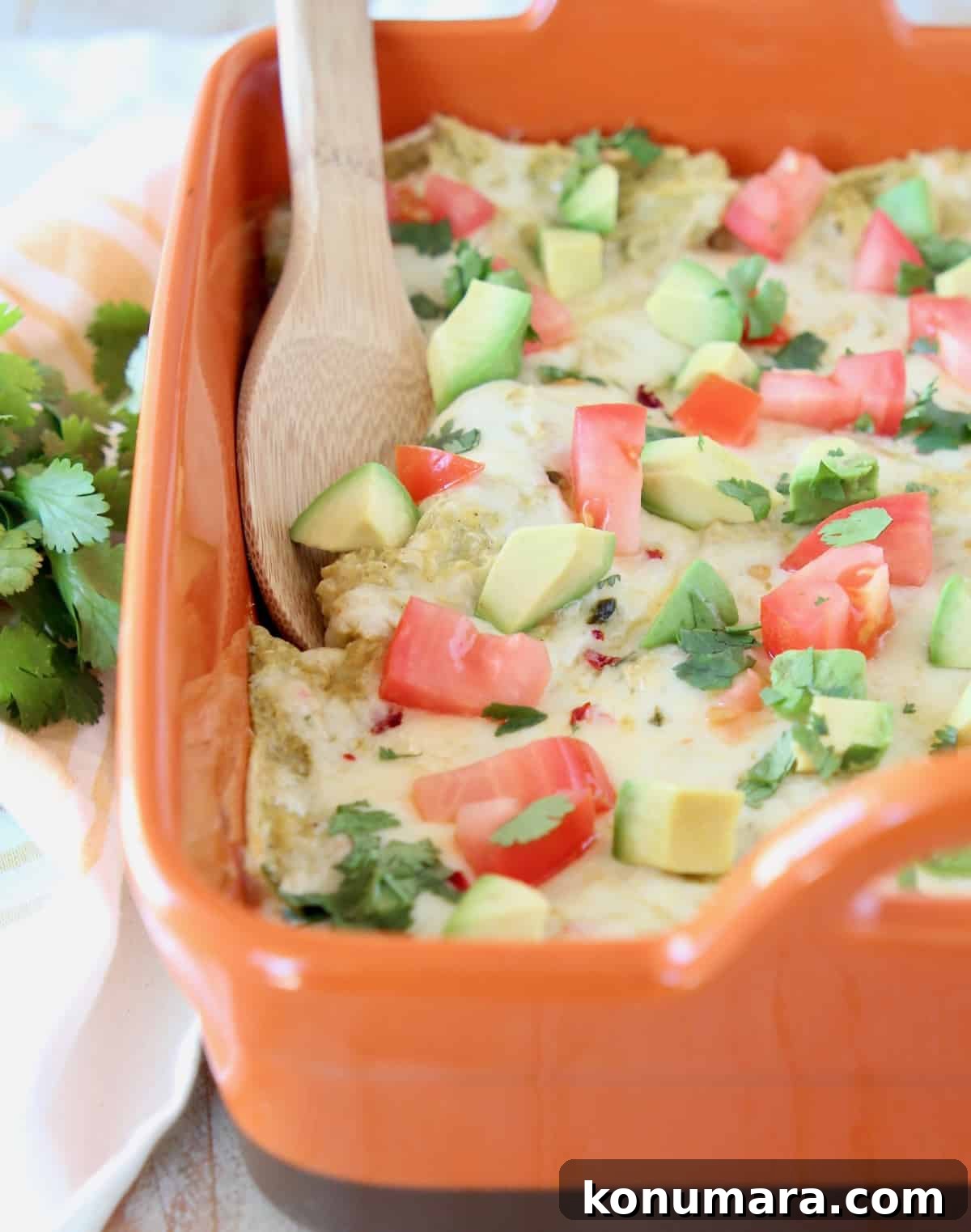 Baked Chicken Enchilada Casserole Recipe 2 Enchilada casserole in orange baking dish with wooden spoon