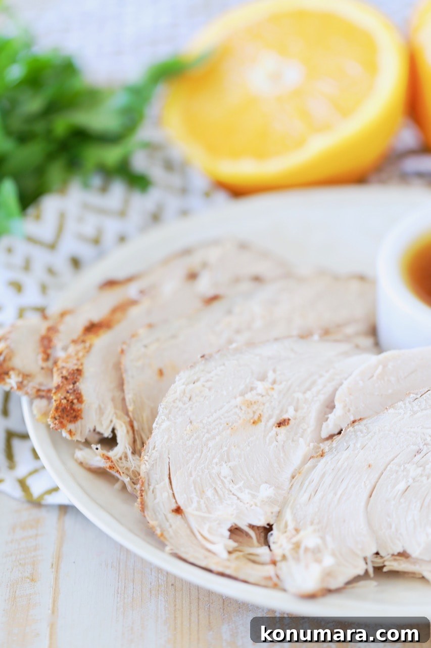 Slices of spice rubbed turkey breast on white plate with side of orange bourbon sauce and sliced orange