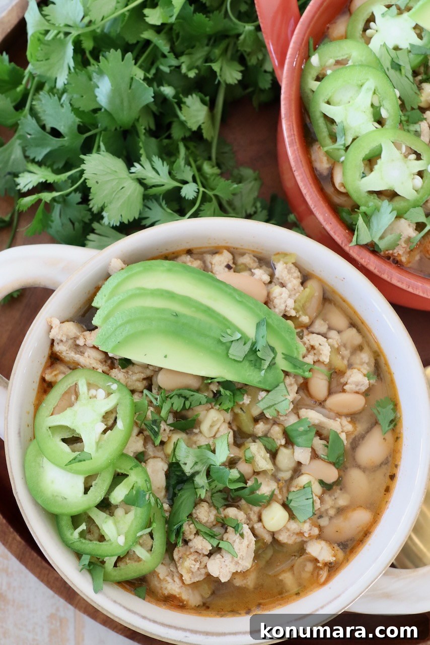 white chicken chili in bowls topped with sliced jalapenos and avocado