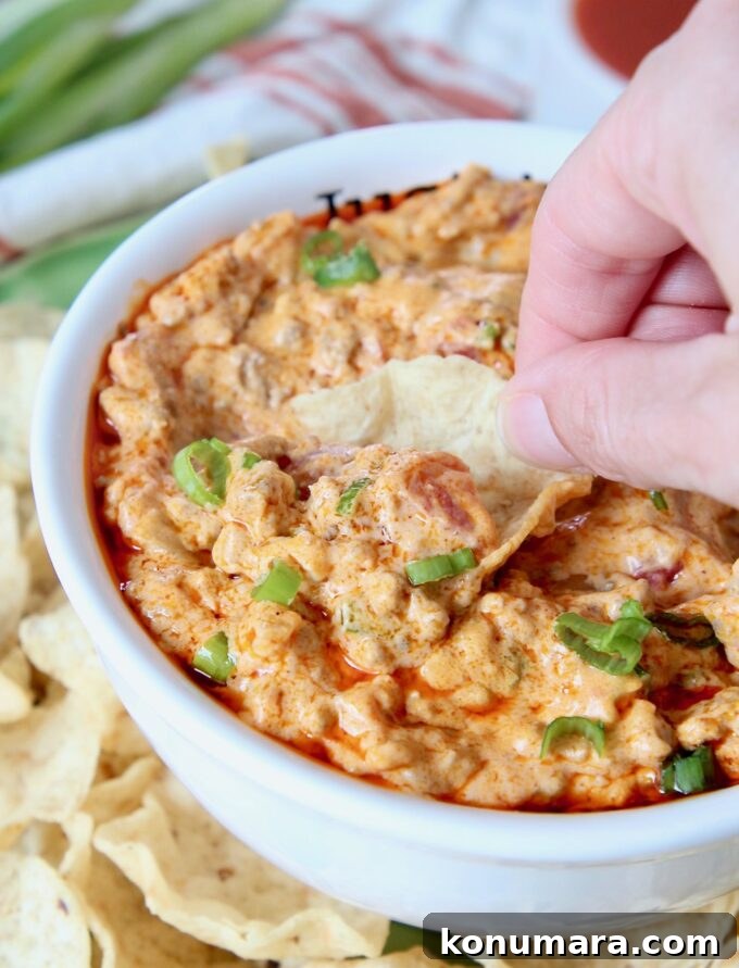 Spicy Buffalo Cheeseburger Dip Recipe 4 hand dipping chip into cheeseburger dip