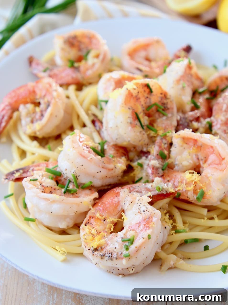 Lemon Garlic Butter Shrimp Scampi 4 Shrimp over pasta, topped with chives and lemon zest on white plate
