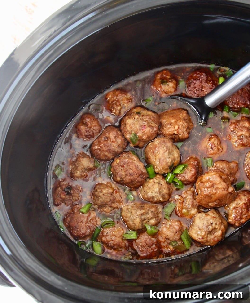 Slow Cooker Korean BBQ Meatballs with Gochujang Glaze 2 Korean meatballs in slow cooker with Korean BBQ sauce and serving spoon