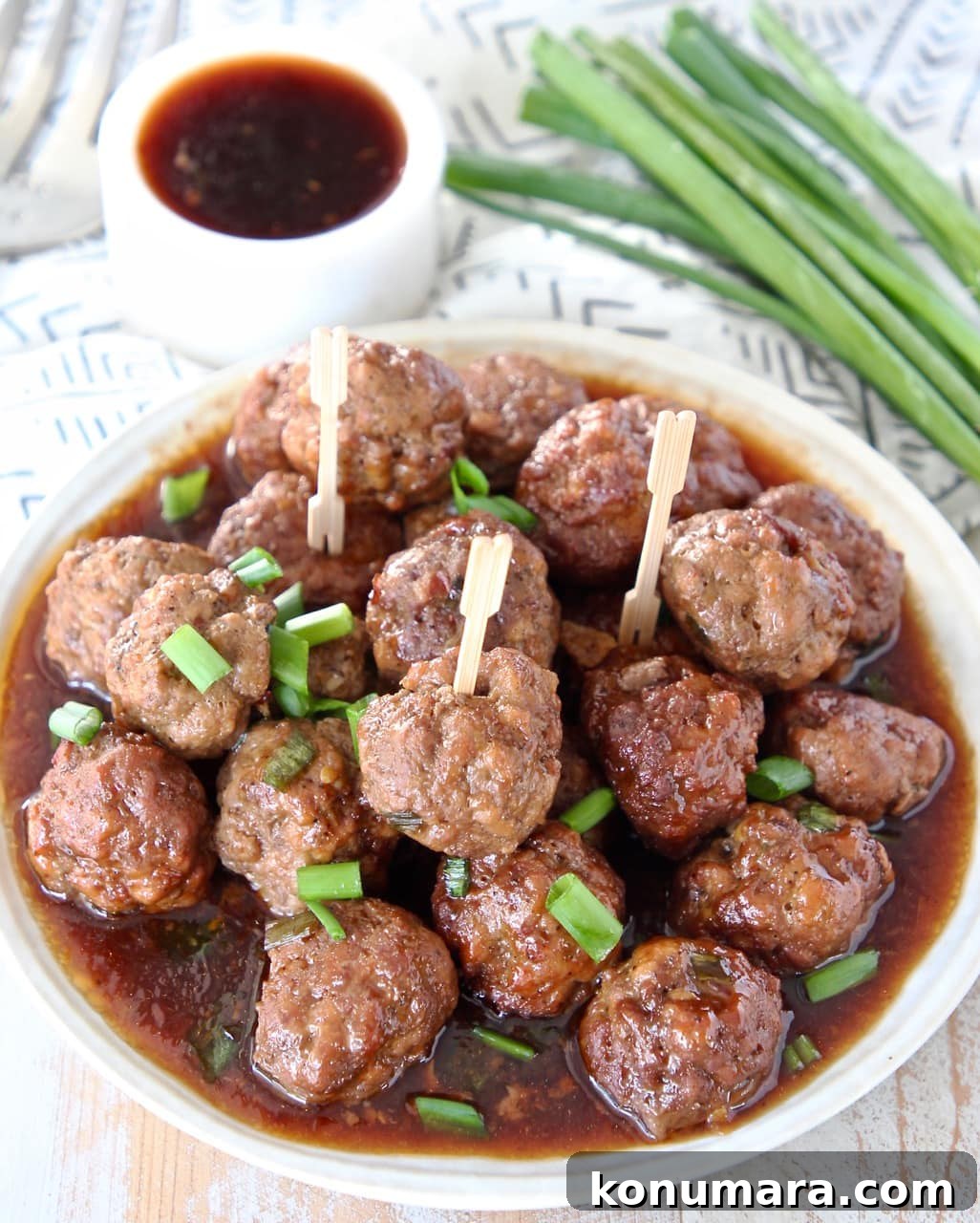 Slow Cooker Korean BBQ Meatballs with Gochujang Glaze 6 Korean BBQ meatballs on a plate with Korean bbq sauce on the side and green onions