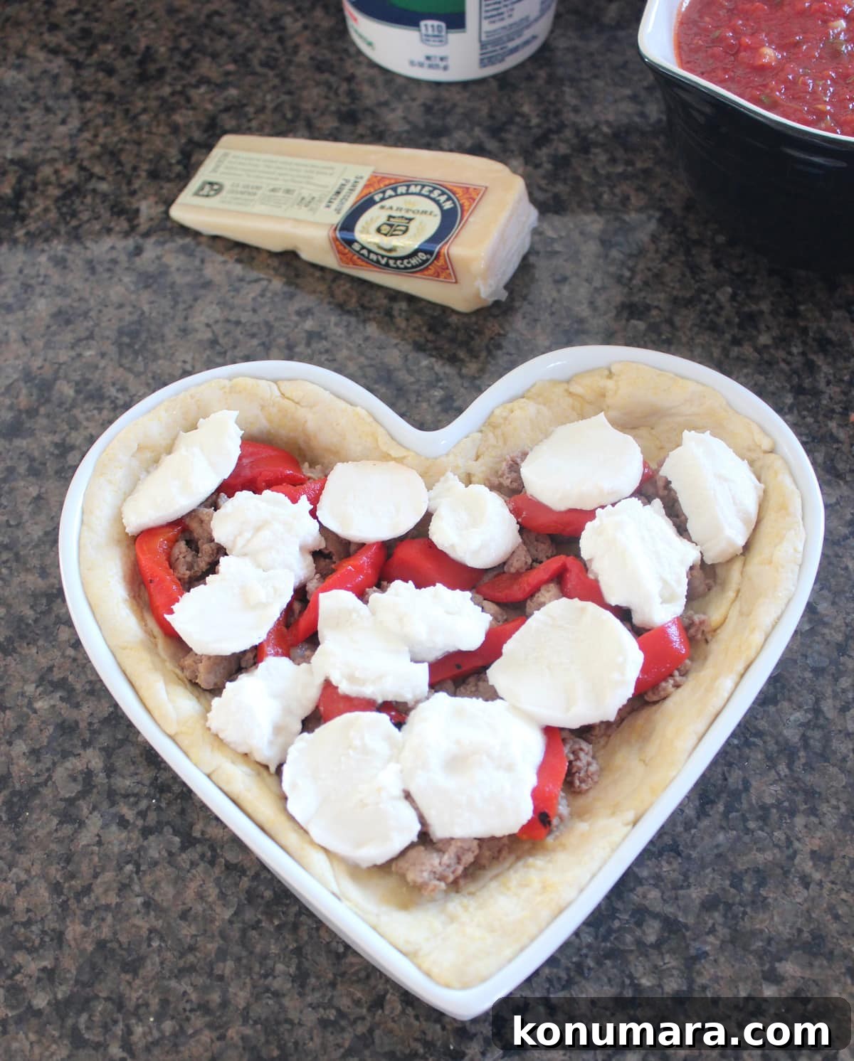 Heart-Shaped Pizza Recipe for Date Night 7 Fresh mozzarella topping sausage and peppers in a pizza shaped like a heart.