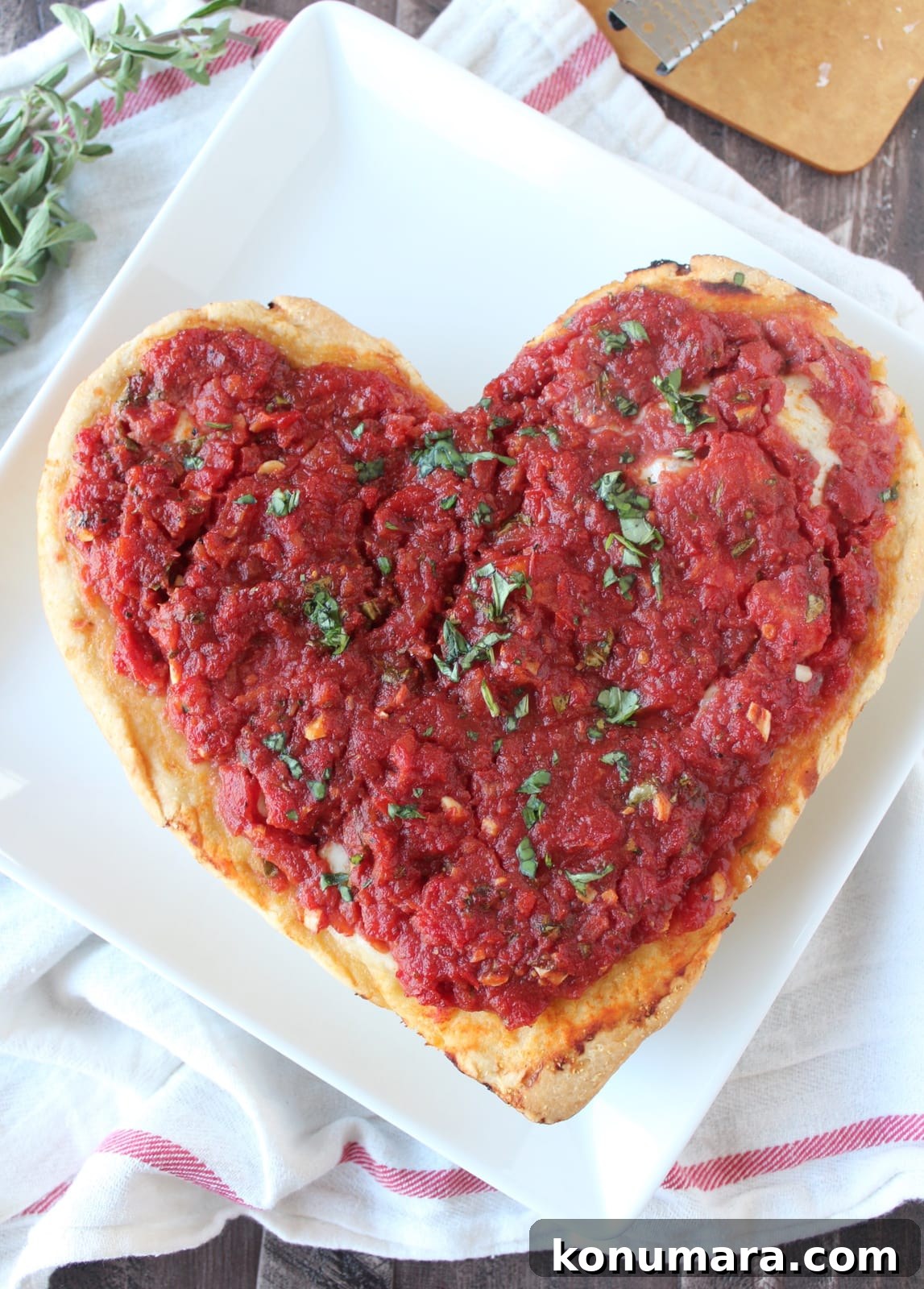 Heart-Shaped Pizza Recipe for Date Night 9 a pizza shaped like a heart on a white plate.