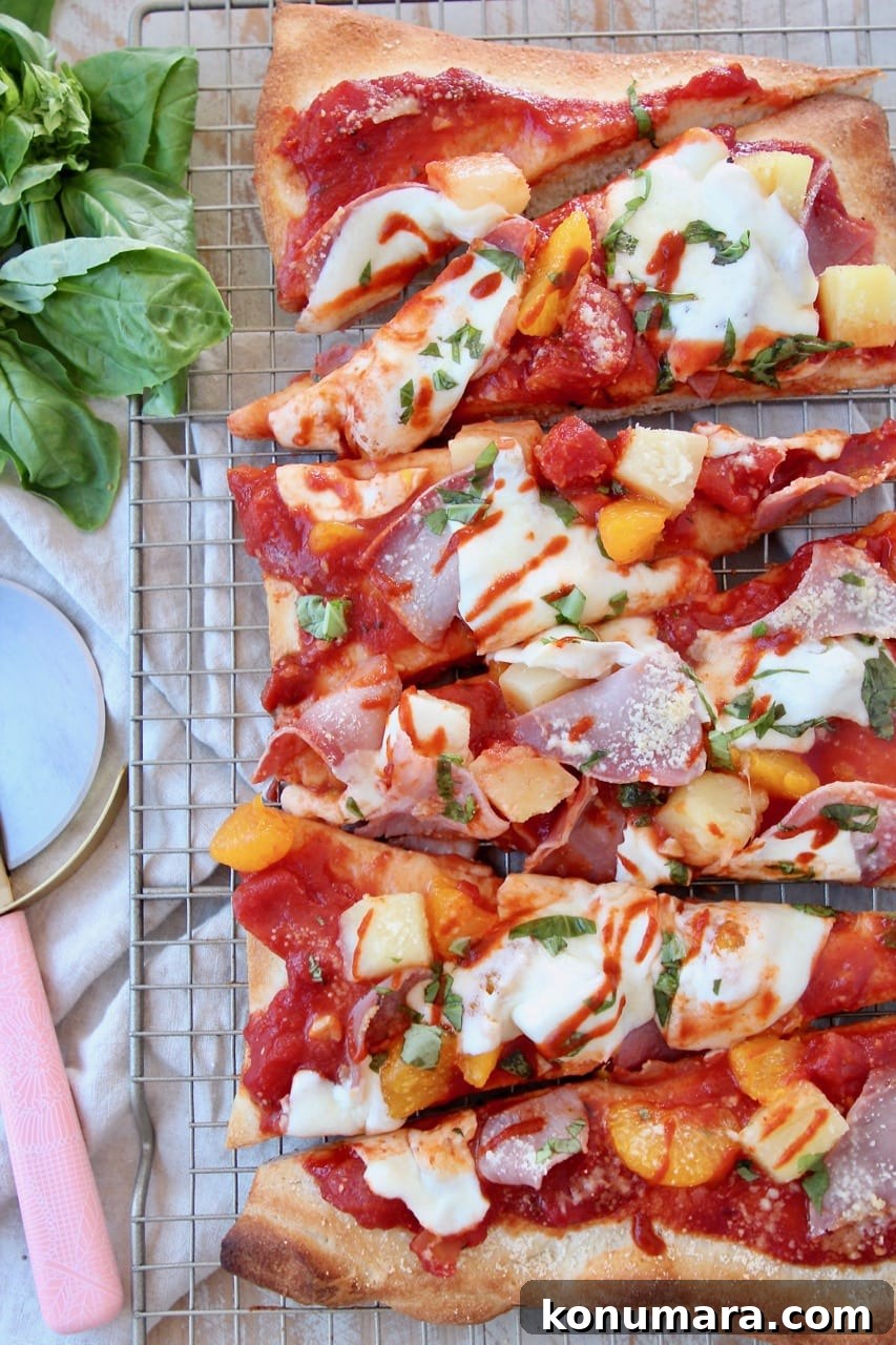 Hawaiian pizza sliced into pieces on wire baking rack