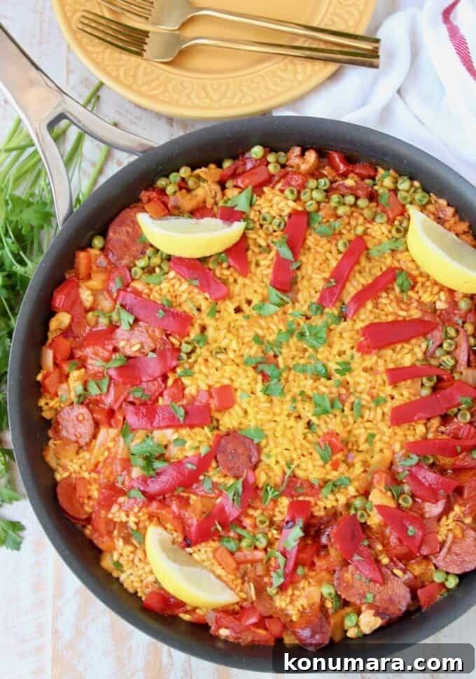 Authentic Spanish Chorizo and Chicken Paella Recipe 2 Overhead image of paella in skillet topped with sliced peppers and lemon wedges