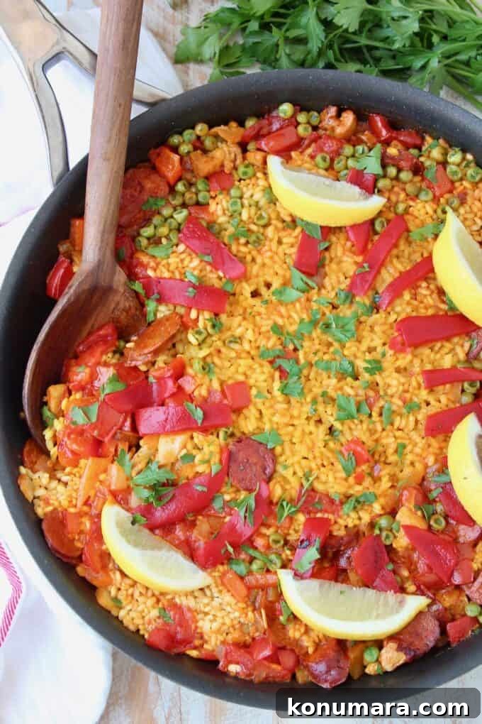 Authentic Spanish Chorizo and Chicken Paella Recipe 6 Overhead image of paella in skillet with wooden serving spoon