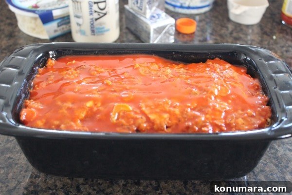 Spicy Buffalo Chicken Meatloaf with Blue Cheese 6 buffalo sauce on top of meatloaf in a loaf pan
