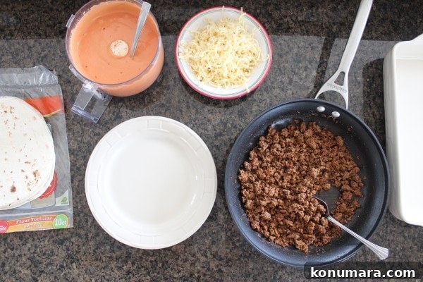 cooked ground beef, shredded cheese, tortillas, and sriracha sauce lined up on a countertop