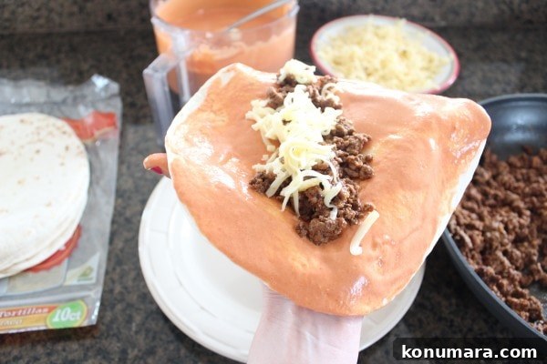 Creamy Sriracha sauce on a tortilla filled with ground beef and shredded cheese