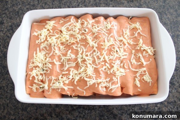 enchiladas in a creamy sriracha sauce in a baking dish covered with cheese