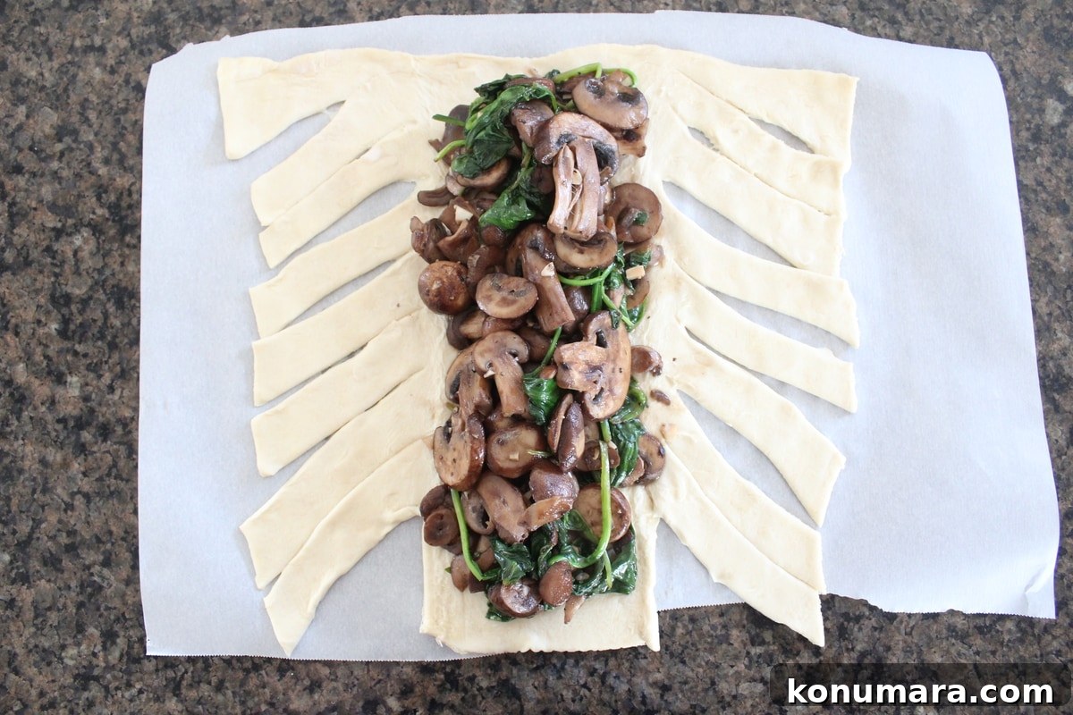 sliced mushrooms and spinach on top of puff pastry dough