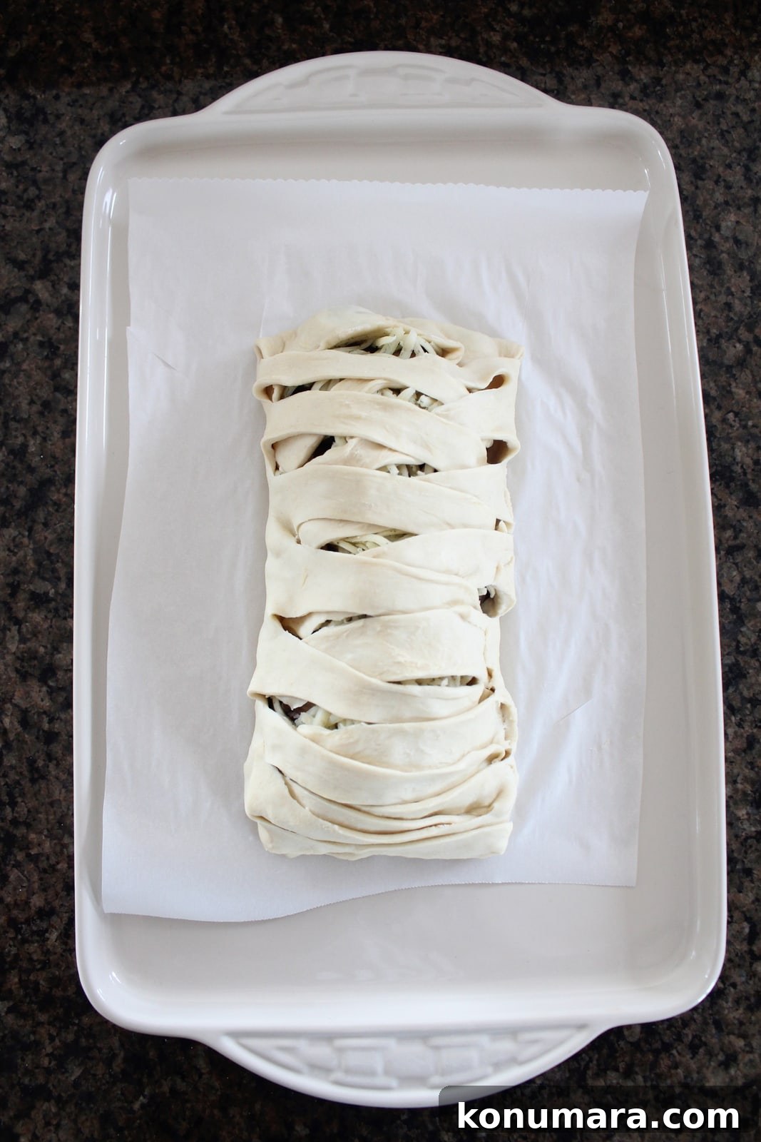 baked braided filled puff pastry on plate with fresh rosemary