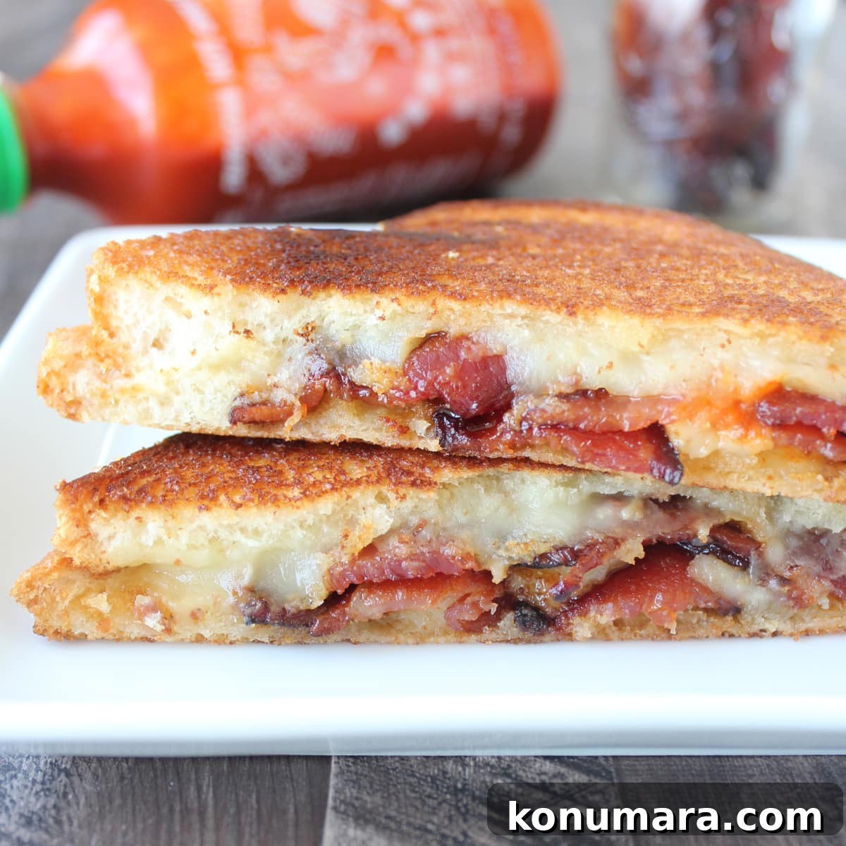 bacon grilled cheese sandwich cut in half and stacked up on a plate