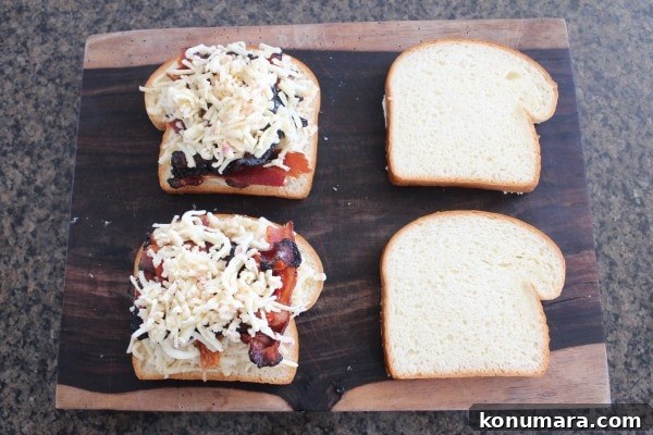 slices of bread topped with cheese and strips of bacon on a wood cutting board