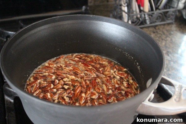 Salted Caramel Praline French Toast Recipe 7 Pecans in a caramel sauce in a pot on the stove.
