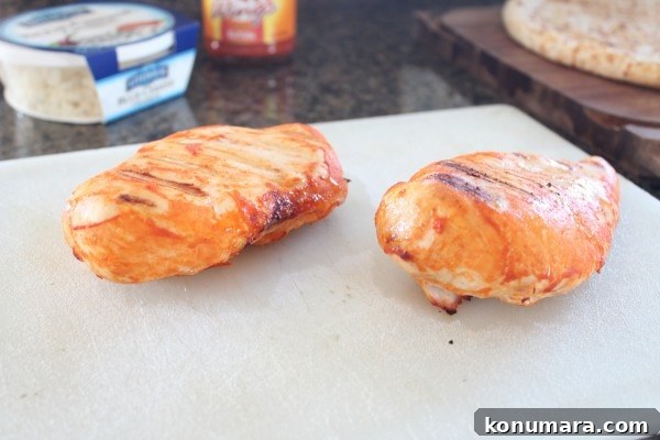 Buffalo Chicken Dip Pizza Recipe 4 Two cooked chicken breasts resting on a white surface.