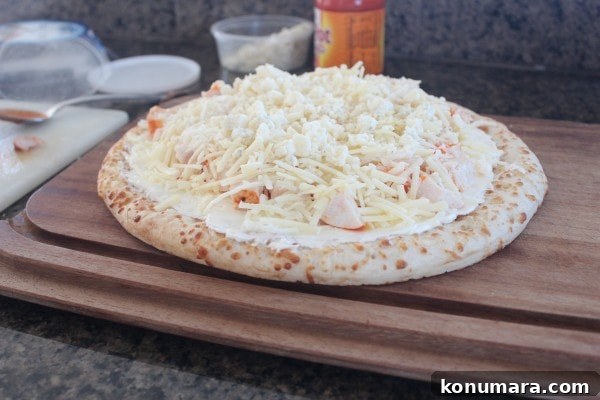 Buffalo Chicken Dip Pizza Recipe 7 Uncooked Buffalo Chicken Dip Pizza on a wooden cutting board.