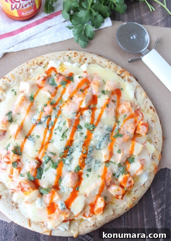 Buffalo Chicken Dip Pizza Recipe 10 Buffalo Chicken Dip Pizza on a wooden surface next to a pizza cutter.