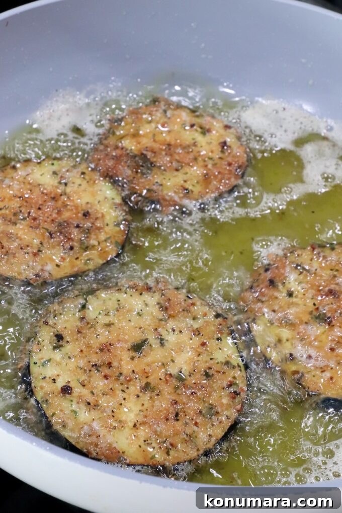 breaded slices of eggplant frying in oil in a pan