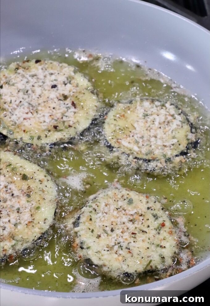 breaded slices of eggplant frying in oil in a pan