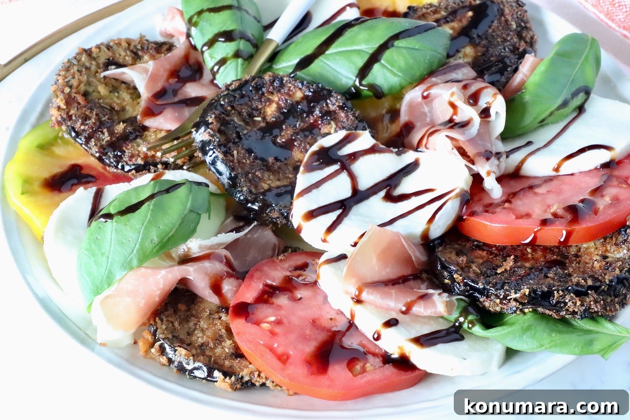 A colorful salad featuring breaded eggplant slices, fresh mozzarella, ripe tomatoes, basil leaves, and prosciutto, drizzled with balsamic glaze.