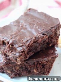 Two chocolate brownies stacked on top of each other on a plate