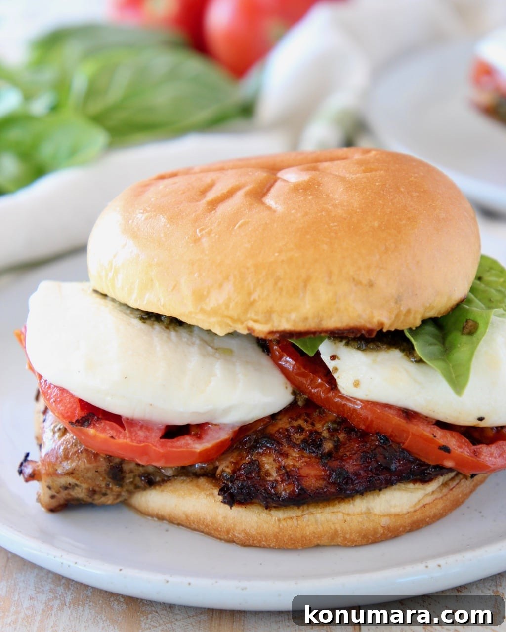 Grilled Chicken Caprese Sandwich with Fresh Mozzarella and Basil 5 Grilled chicken sandwich with tomatoes, basil and mozzarella cheese on white plate