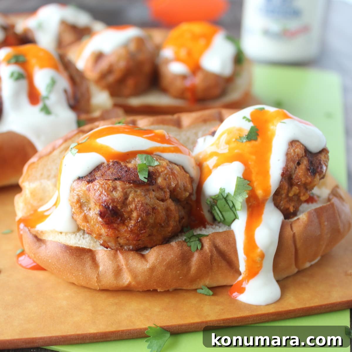 Hot dog bun topped with turkey meatballs and drizzled with buffalo sauce and blue cheese dressing.