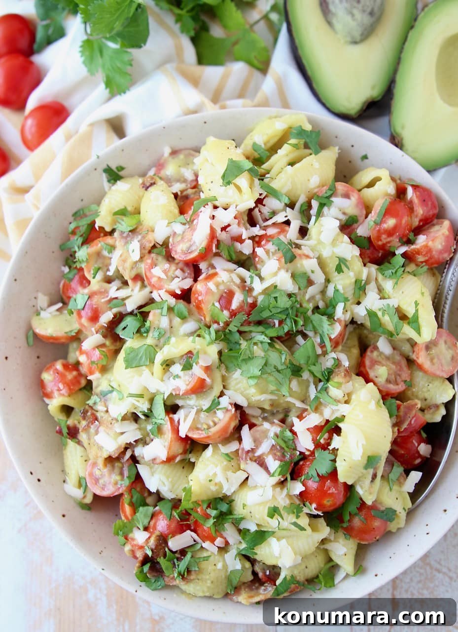 Overhead shot of BLT pasta salad in a bowl, topped with parmesan cheese and fresh basil