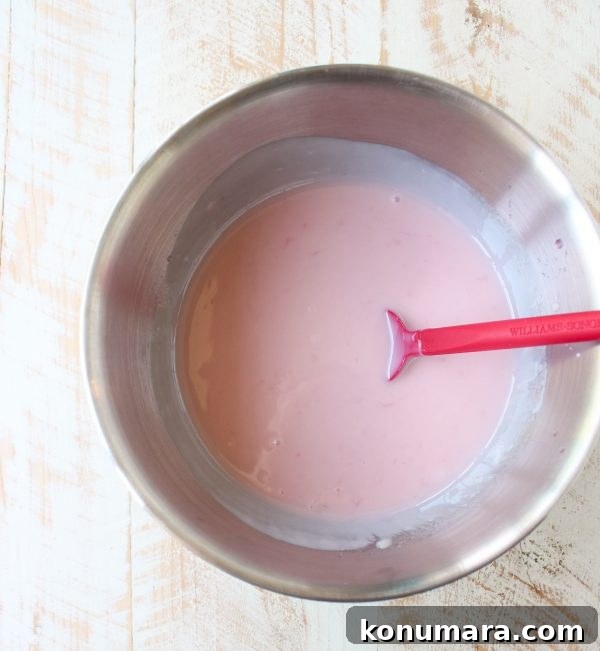 pink lemonade pie filling in a metal bowl with a red spatula