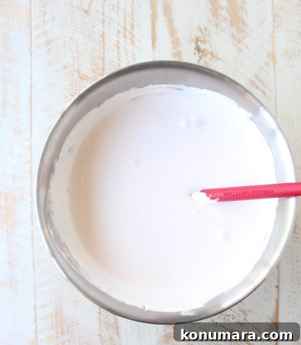 pink lemonade pie filling in a metal bowl with a red spatula