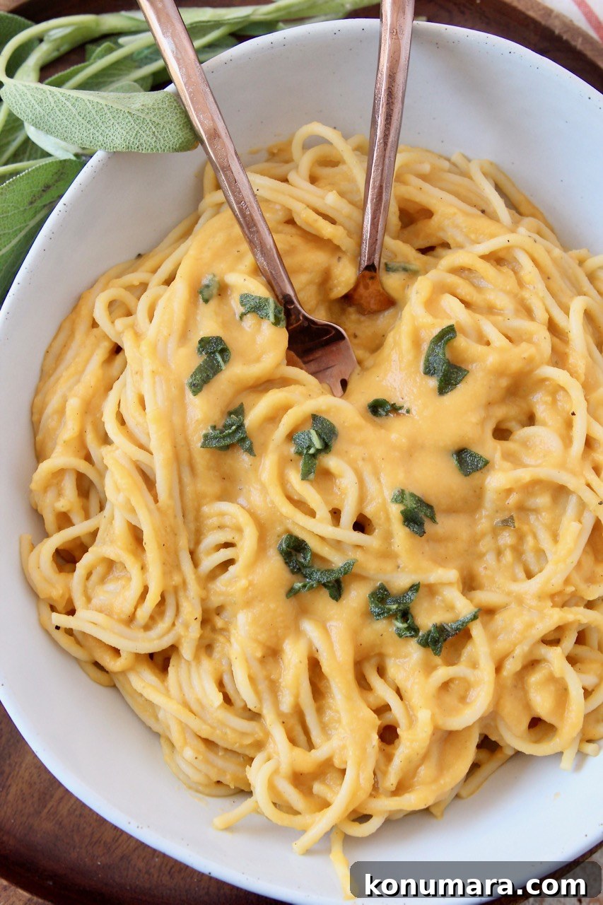 spaghetti noodles tossed with butternut squash sauce in bowl with two forks