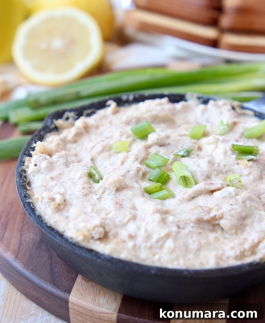 Hot crab dip in cast iron skillet, sitting on wood cutting board