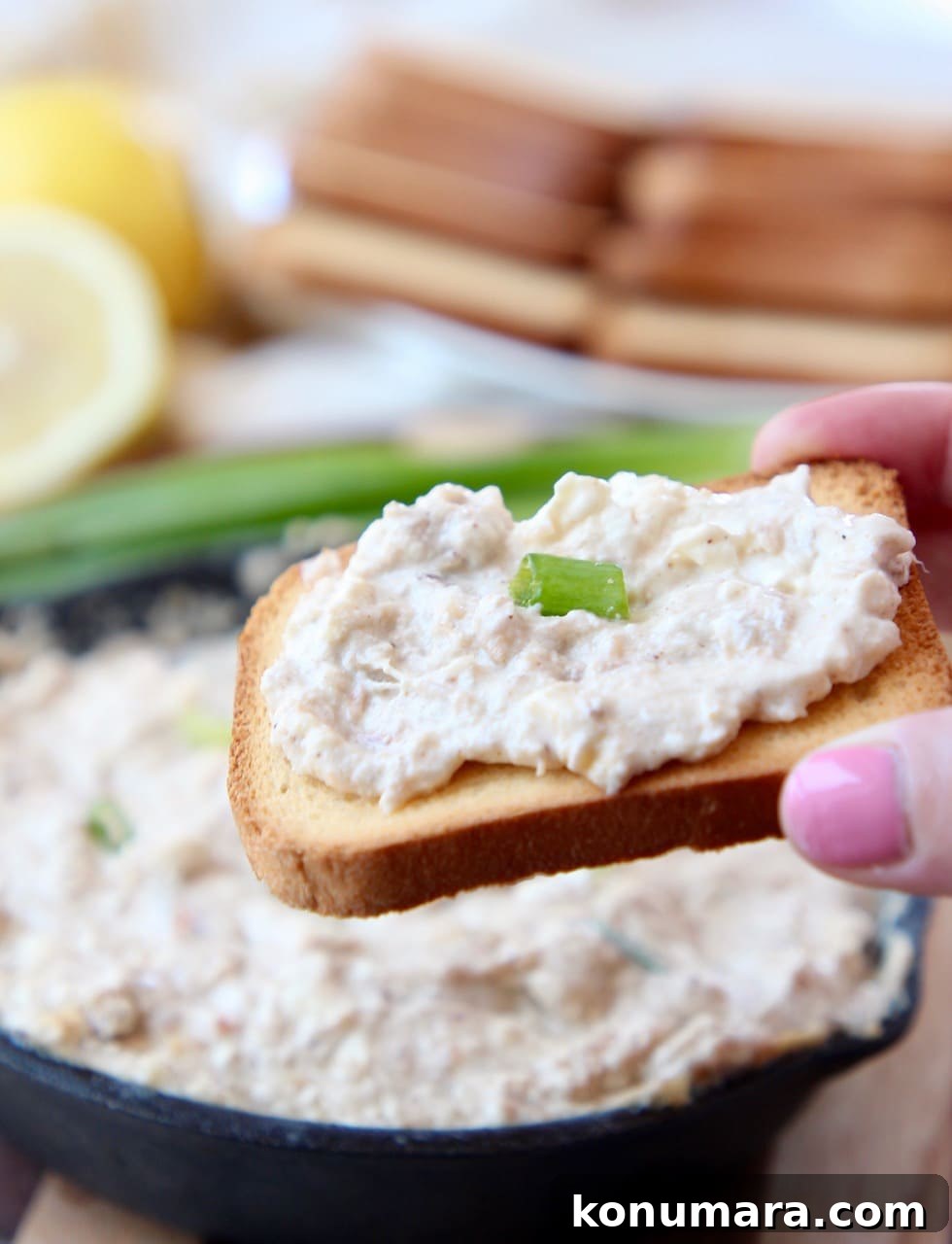 Hand holding brioche toast, topped with hot crab dip