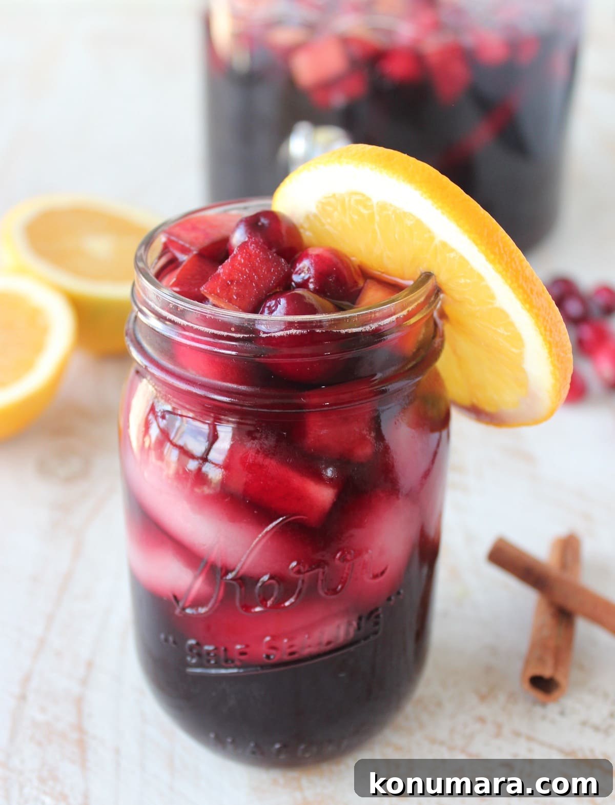 Cranberry Apple Sangria Recipe for Festive Fall Gatherings 2 Cranberry Apple Sangria in a mason jar with an orange slice on the rim of the glass