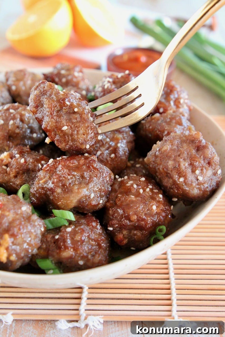 Chinese Meatballs in bowl, with gold fork holding up one meatball