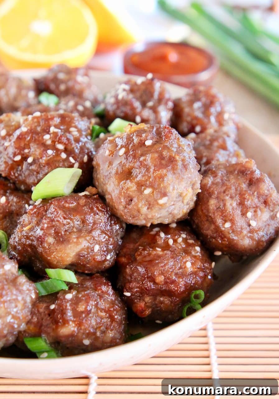 Chinese meatballs in bowl, topped with sesame seeds and green onions