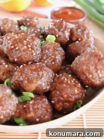 Chinese orange glazed meatballs in bowl with sesame seeds and green onions on top