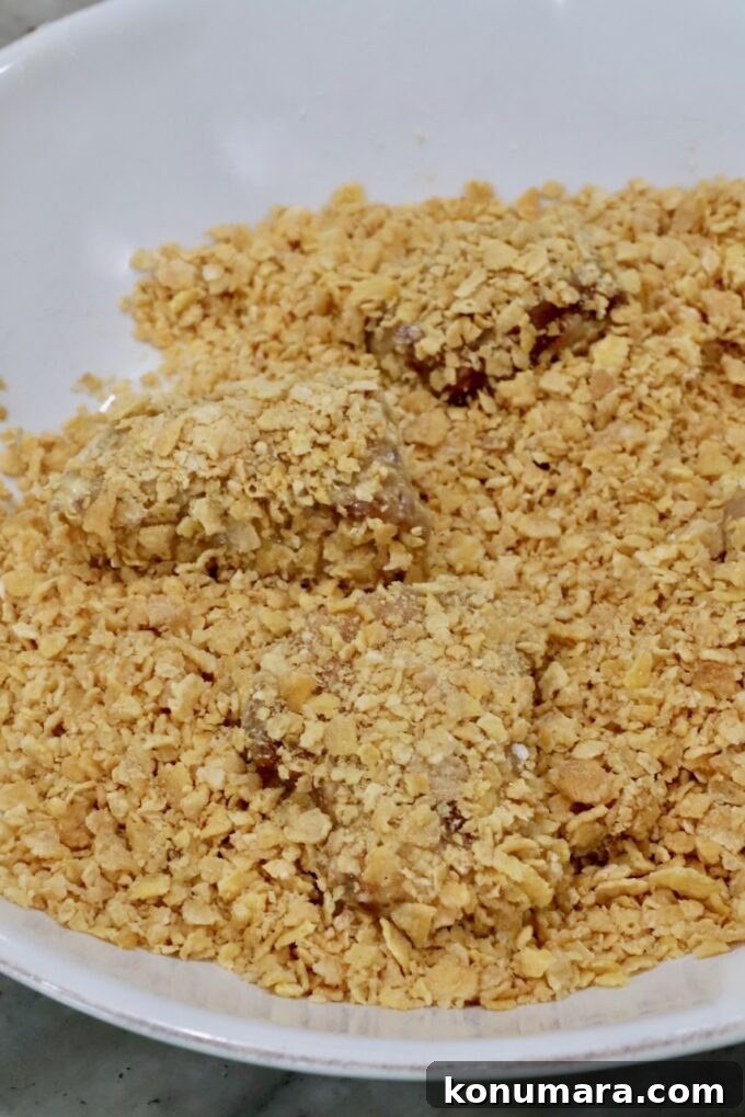 breaded pieces of chicken in a bowl of crushed corn flakes