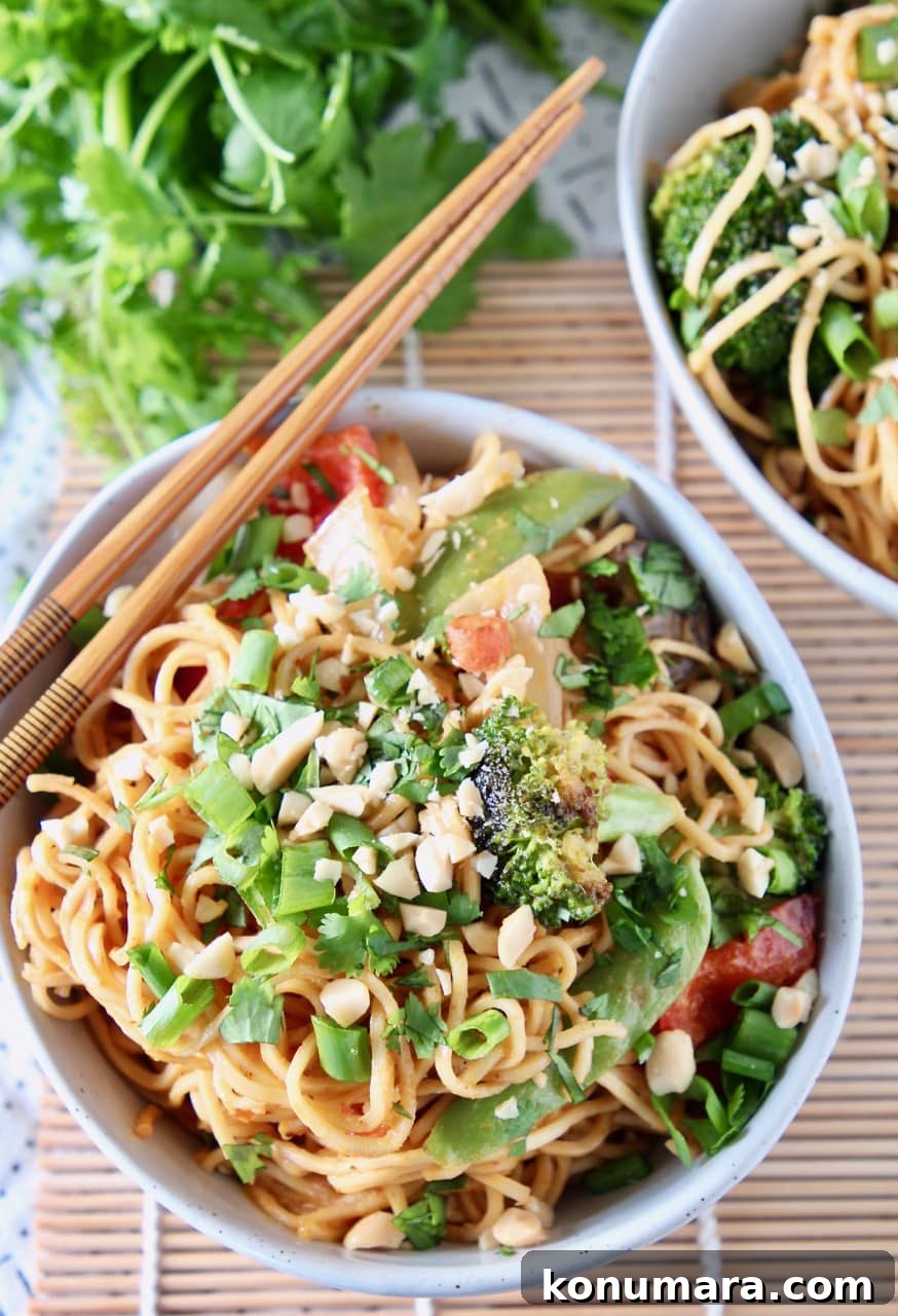 Noodles and vegetables in bowl with chopsticks on the edge of the bowl