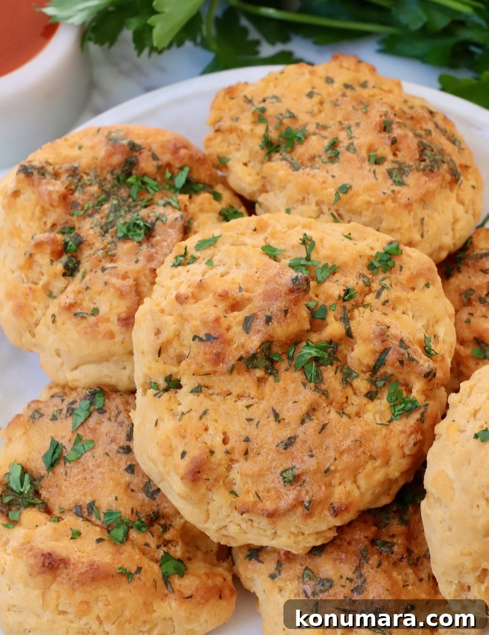 Buffalo Cheddar Biscuits Recipe 2 cheddar biscuits stacked up on a plate topped with fresh chopped parsley