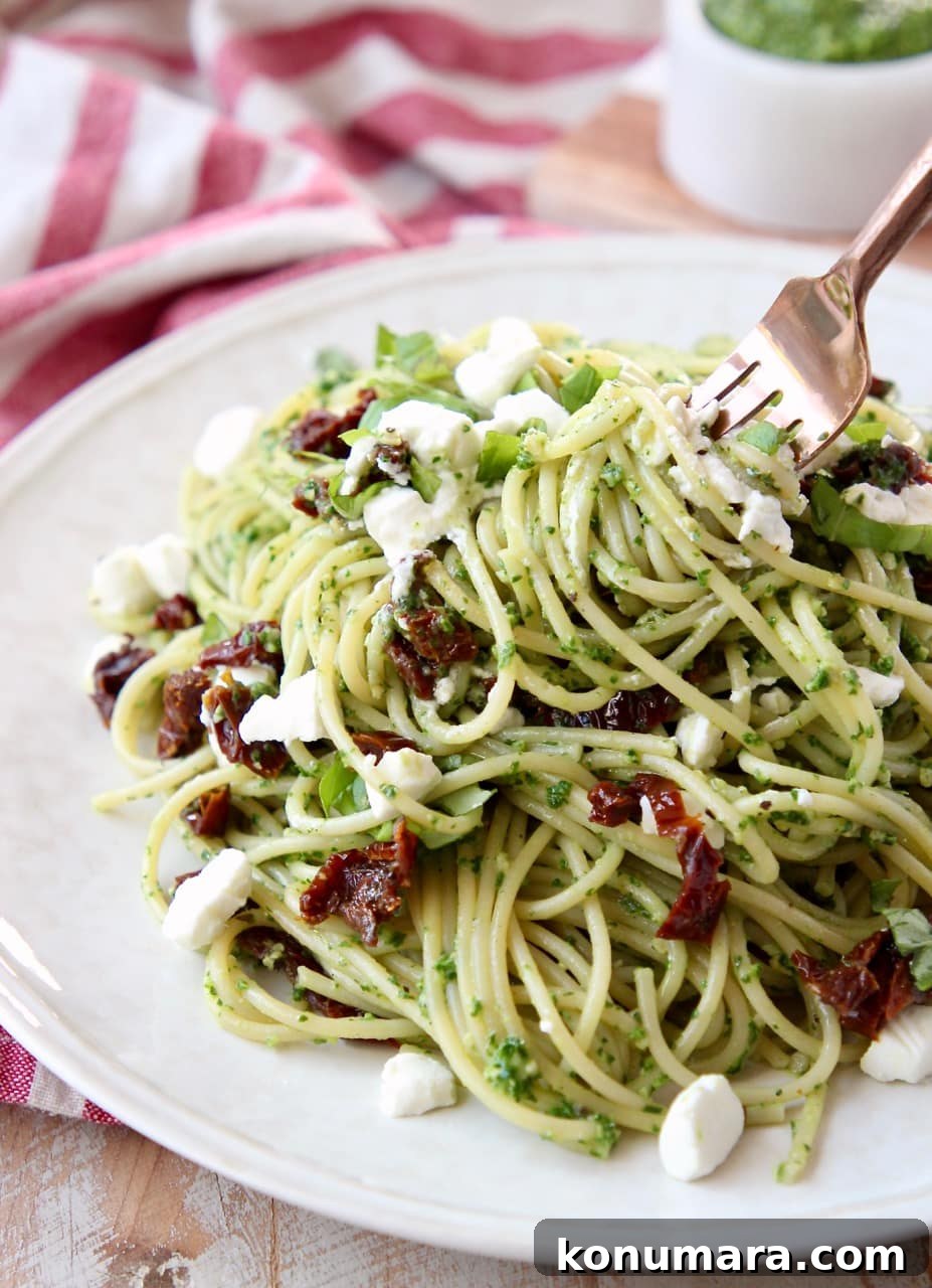 Kale Pesto Spaghetti with Creamy Goat Cheese 3 Pesto spaghetti with sun dried tomatoes on white plate with a gold fork twirling the spaghetti on the plate