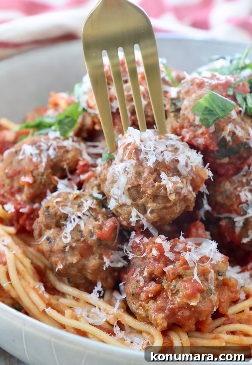 Slow Cooker Meatballs with Marinara Sauce Recipe 6 fork picking up meatball from bowl of spaghetti and meatballs
