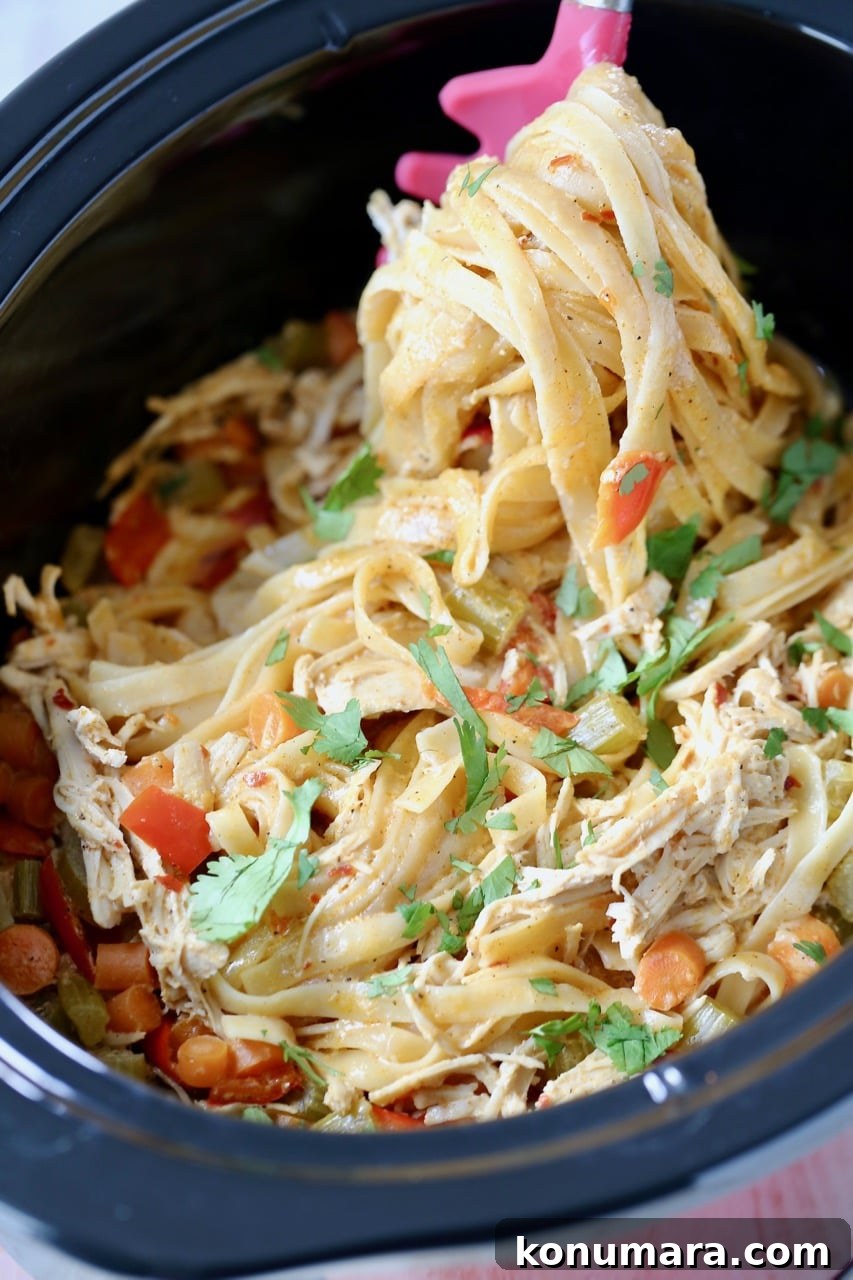 Slow Cooker Buffalo Chicken Alfredo Recipe 2 Buffalo chicken alfredo pasta in a crock pot with a spoon scooping the pasta out of the crock pot