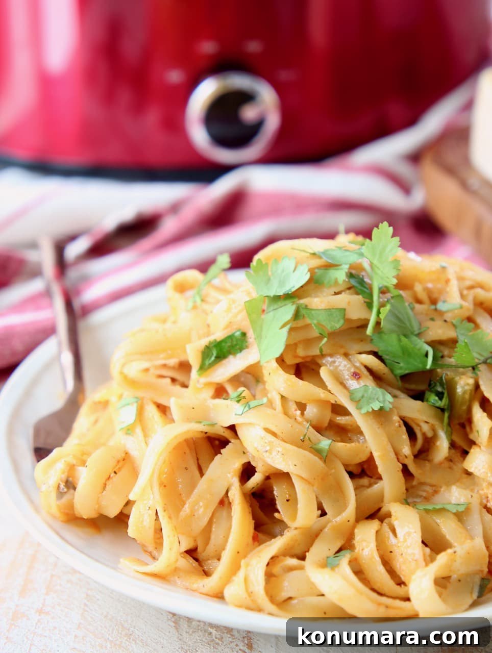 Slow Cooker Buffalo Chicken Alfredo Recipe 3 Buffalo chicken alfredo on a plate with copper fork, on top of red and white striped towel with red crock pot in background