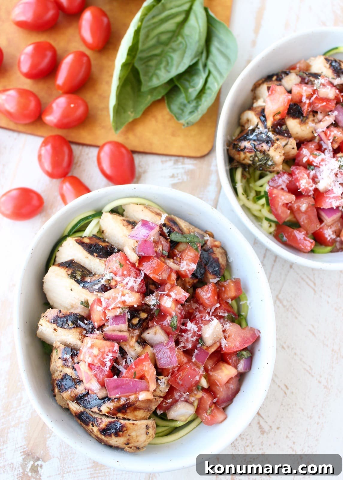 Overhead shot of bruschetta chicken in bowls with zucchini noodles and fresh basil