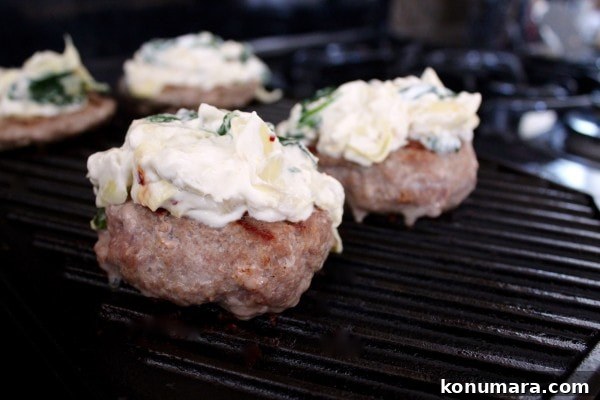 Spinach and Artichoke Turkey Burger Recipe 7 turkey burgers on a grill pan topped with spinach artichoke dip